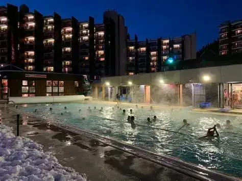 La piscine extérieure chauffée, devant la résidence, en soirée