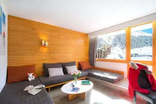 Salon de l'appartement avec lits banquettes et baie vitrée sur les pistes