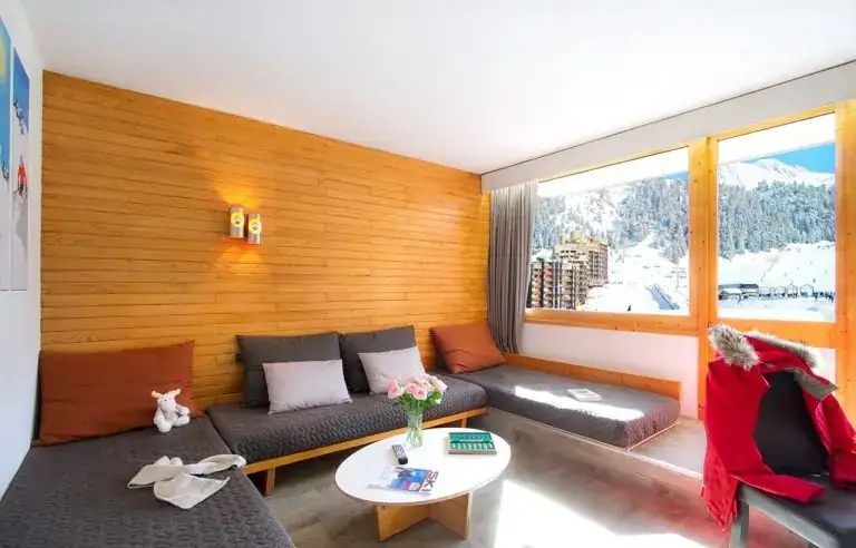 Salon lumineux en bois avec grande baie vitrée sur les pistes